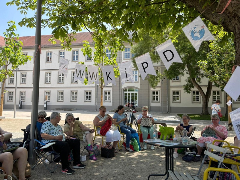 Personen sitzen im Schatten und stricken auf dem Arsenalplatz
