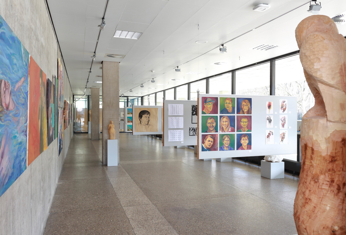 Skulpturen und Gemälde werden in einem langen, hellen Raum präsentiert.