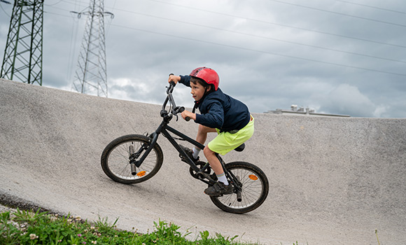 Junge mit Fahrrad auf einem Pumptrack.