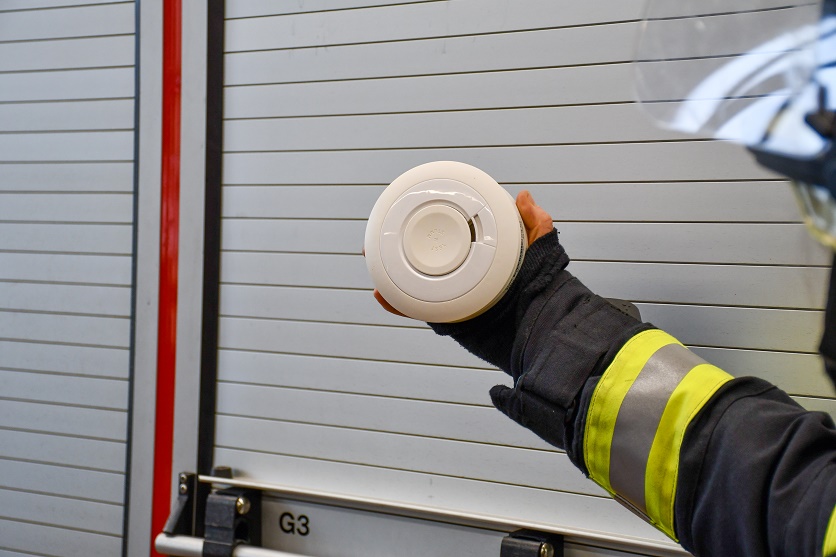 Rauchwarnmelder in der Hand eines Feuerwehrangehörigen