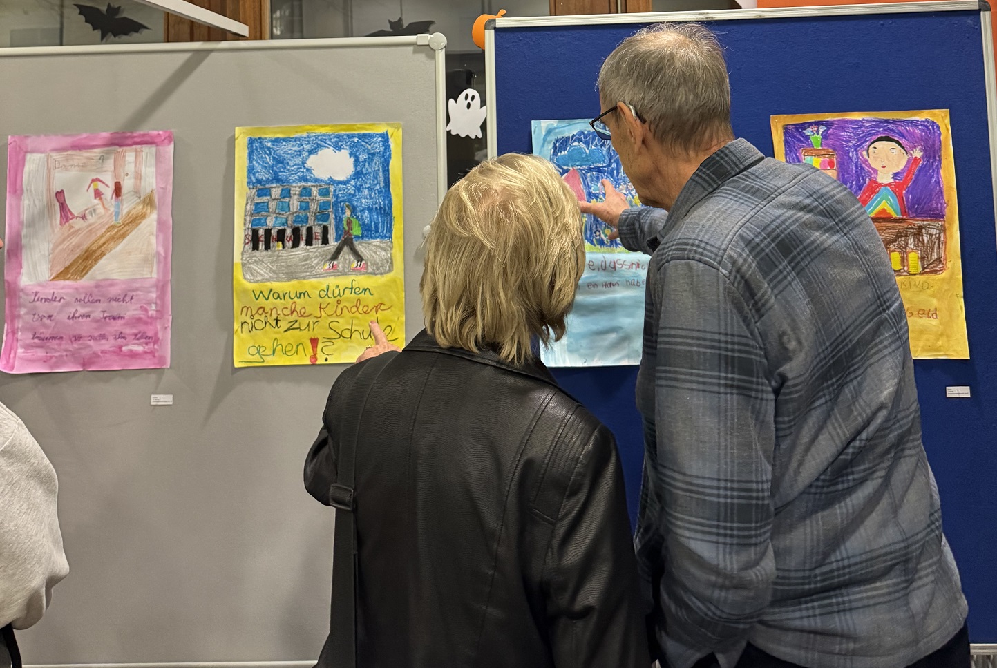 Zwei Personen – ein älterer Herr und eine Dame – betrachten die ausgehängten Bilder