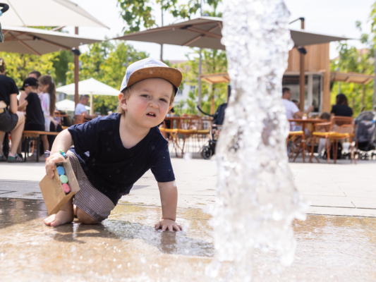 Kind kühlt sich an Wasserfontäne ab